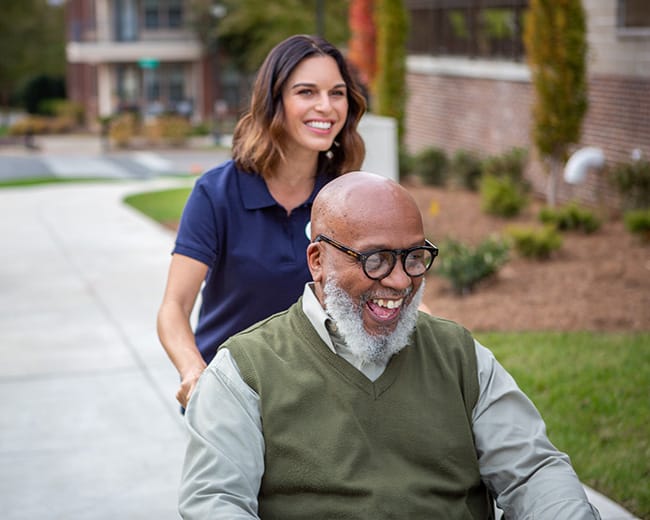 caregiver pushing resident in wheelchair