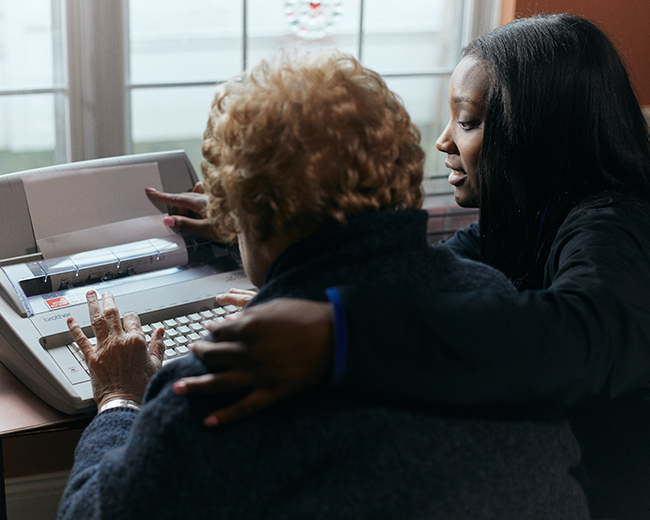 caregiver helping resident use typewriter
