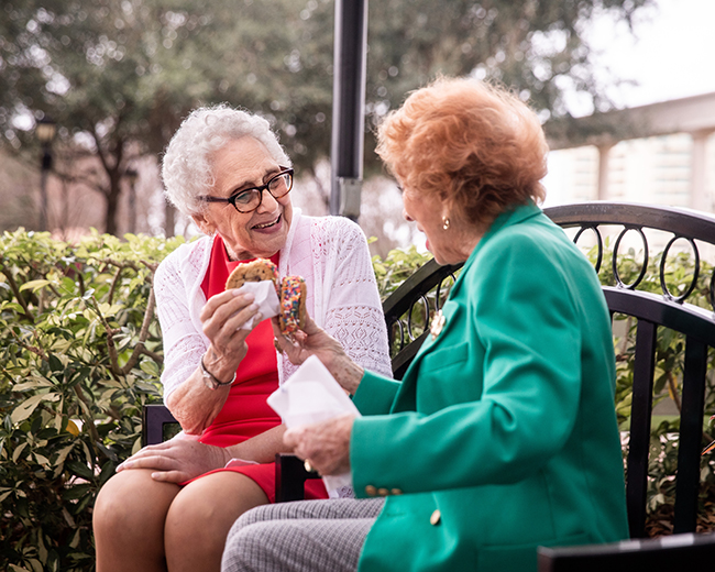 Friends eating cookies on bench outside