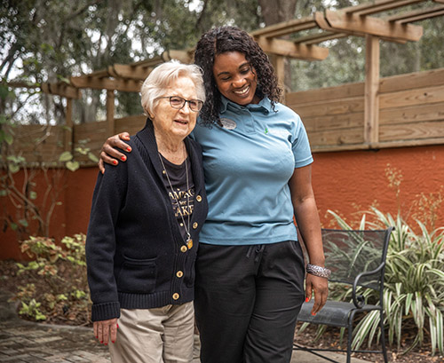 caregiver with woman in courtyard