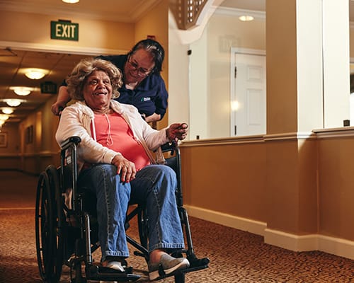 caregiver pushing resident in wheelchair