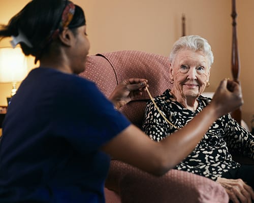 caregiver helping resident put on a necklace