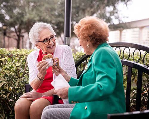 friends eating cookies on bench outside