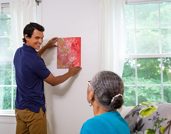 caregiver helping hang painting