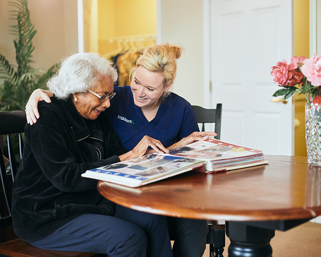woman looking at scrapbook with caregiver