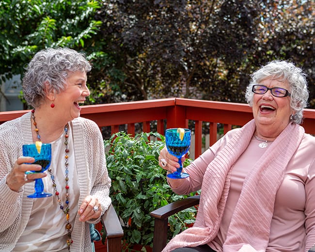 women laughing and drinking wine