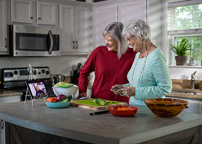 Two older women in the kitchen cooking together.