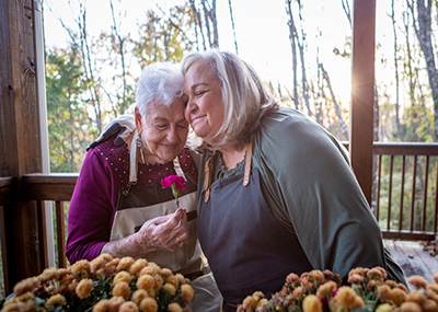 two women hugging and holding a flower