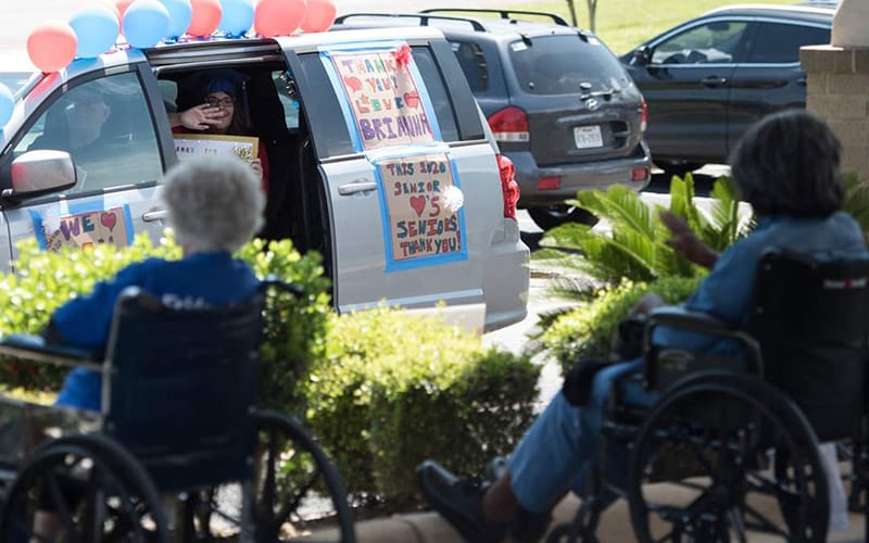 Loved ones wave to residents of Brookdale during a car parade.