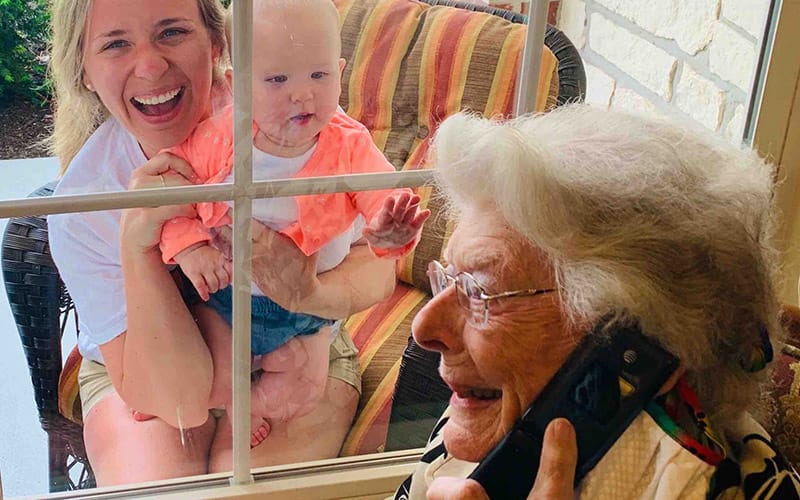  A resident of Brookdale Sandy Springs (Tennessee) enjoys a window visit and phone call with loved ones.